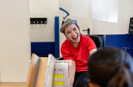 Woman with special needs helmet laughing joyfully during therapy