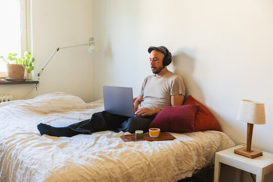 Man Working on Laptop in Bed