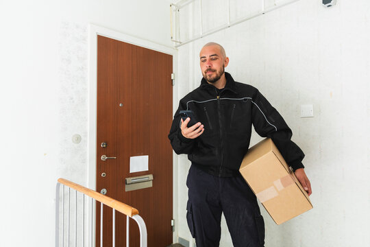 Delivery Courier Checking Smartphone in Hallway