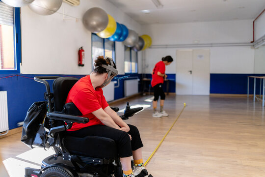Person in wheelchair using assistive device practicing therapy