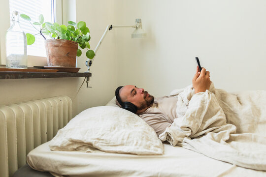 Man Using Smartphone Lying in Bed