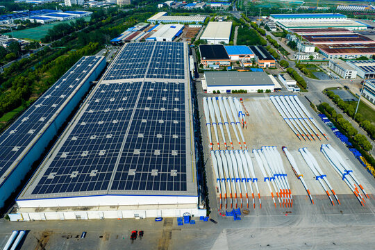 solar rooftop factory yard with wind turbine blades stored outside
