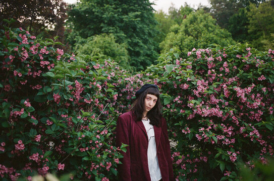 Woman stands among pink flowers in a garden on a summer day