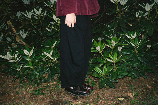 Person standing next to green plants wearing vintage clothing