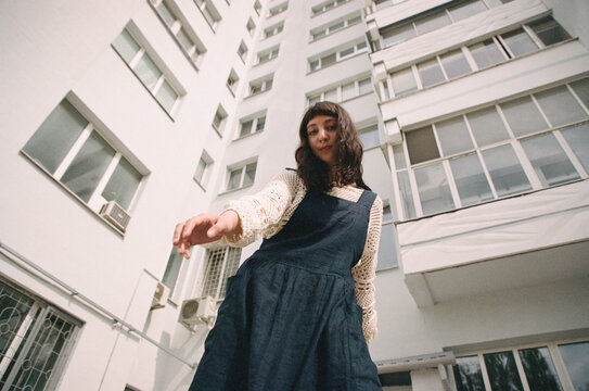 Young woman reaches out while standing in front of a building