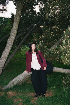 Woman stands by a tree and looks around in park