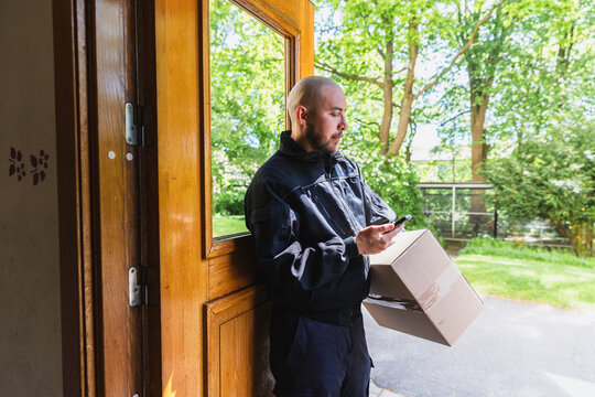 Courier Checking Phone inside Building Entrance