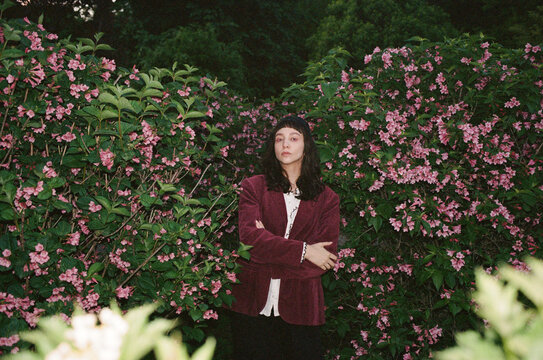 Woman stands among pink flowers in a garden. Direct flash.
