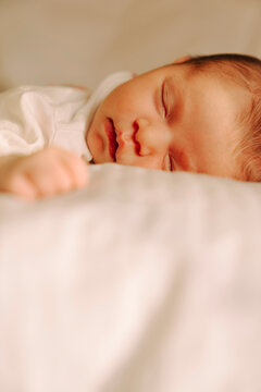 Close up of peacefully sleeping newborn baby on white sheets