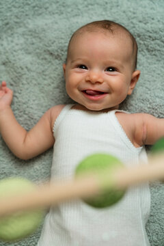 Overhead shot of joyful smiling baby lying on a soft green blanket