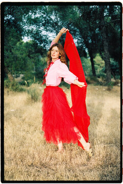 Woman with red fabric in dry field