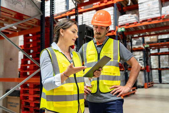 Warehouse workers discussing logistics with digital tablet
