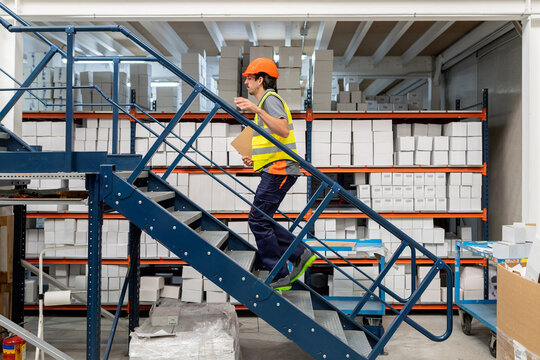 Warehouse worker climbing stairs managing logistics inventory