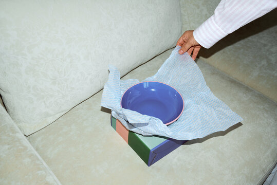 Hand placing a blue bowl on a wrapping paper