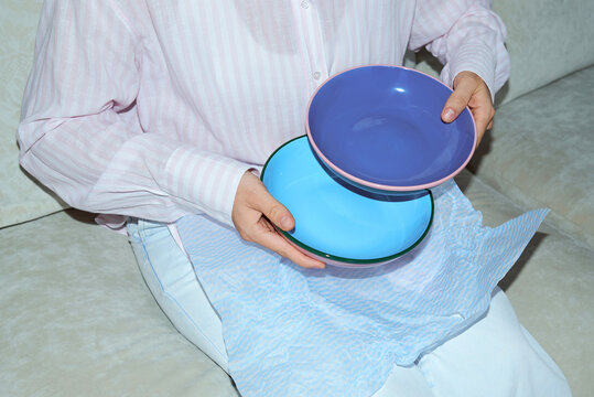 Anonymous woman unpacking two plates in blues tones.