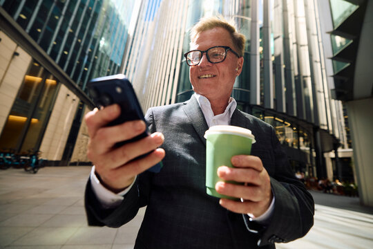 Senior entrepreneur checks his phone outdoors