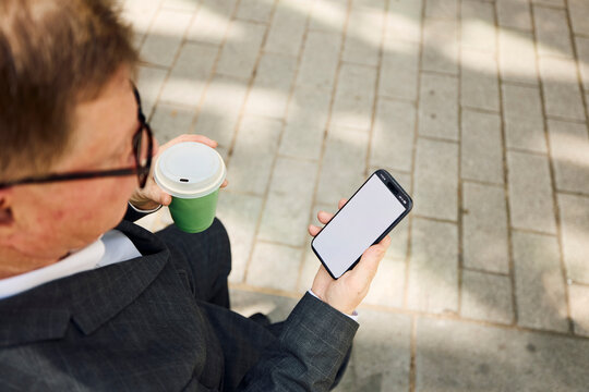 Businessman checks his phone outdoors
