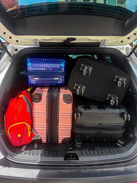 Car trunk packed with colorful suitcases