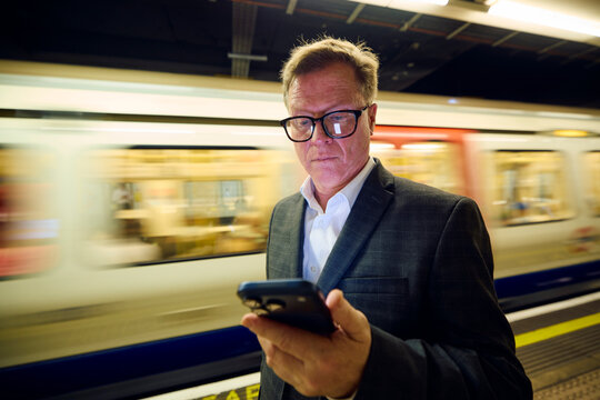 Elegant man checks his phone at the subway platform