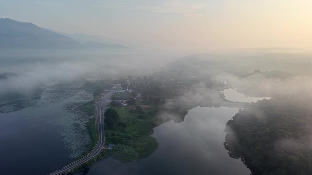 Aerial drone captures dawn's soft glow over misty mountain peaks at Tasik Raban