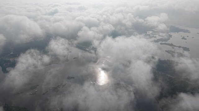 Drone captures clouds above water and islands. Sunlight pierces through the clouds at Tasik Raban