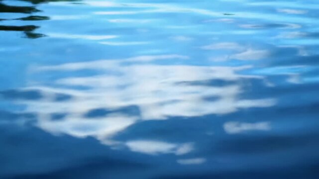 Reflected clouds on water create an abstract, dreamy scene with blue hues and blurry shapes