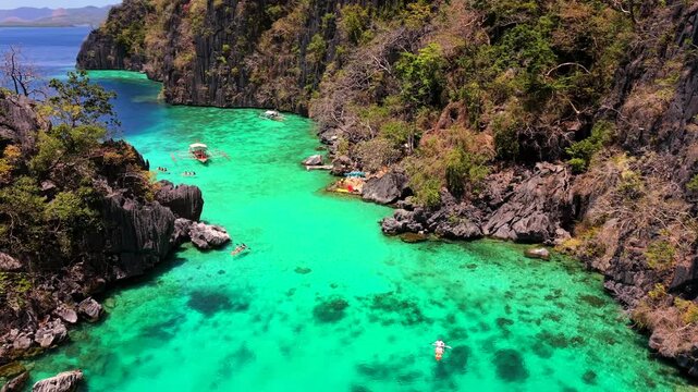 Aerial drone view of Twin Lagoon in Coron, Palawan, Philippines, featuring turquoise water, limestone cliffs, coral reef formations, and tropical island landscape.