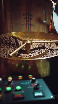 coffee beans roasting process closeup, professional roaster machinery equipment roast brown and golden colored cafe seeds close-up, 4k vertical video