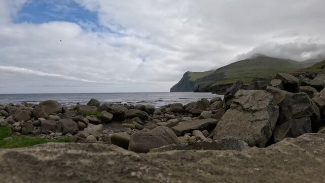 Low angle shot of rocky beach and misty cliffs in Sandur, Faroe Islands