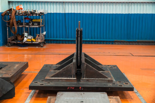 Heavy Industrial Jig Fixture: A robust jig fixture made of dark metal, designed for precision in an industrial workshop setting, with machinery and tools visible in the background.