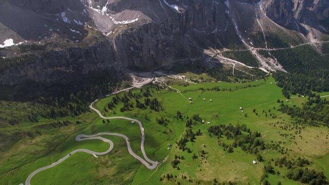 Passo Gardena Dolomites Italy Aerial Drone Tilt Down Flight from Peaks in Clouds to Winding Serpentine Road in Green Alpine Valley Below Majestic Scale Epic Travel Video 4K UHD