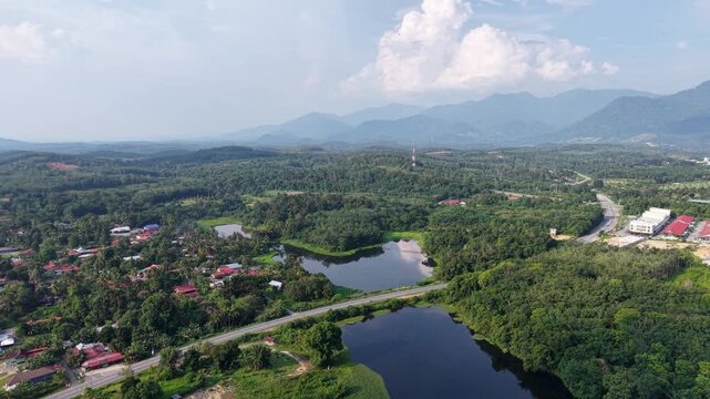 A breathtaking aerial showcasing dense green forest, a winding river, distant mountain range at Tasik Raban