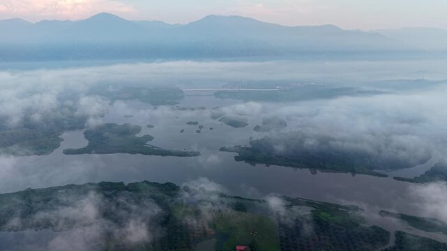 Aerial view of misty river and islands. Soft dawn light on distant mountains at Tasik Raban