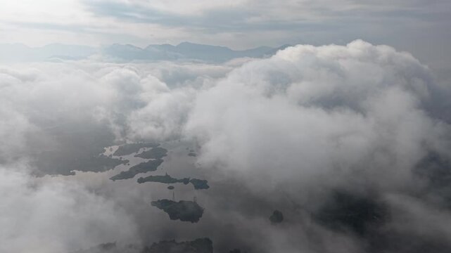 Dense white clouds blanket a sea with hidden islands at Tasik Raban