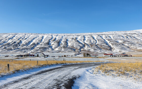 Typical farming community on the Sprengisandsleid route through the central highlands of Iceland, south west of Lake Myvatn. Snow and ice covered road and mountains with blue sky.