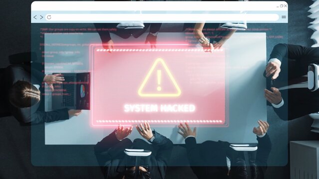 A group of professionals in dark suits discusses strategies around a conference table while a digital screen shows a warning of a cyber attack and system breach. Raster
