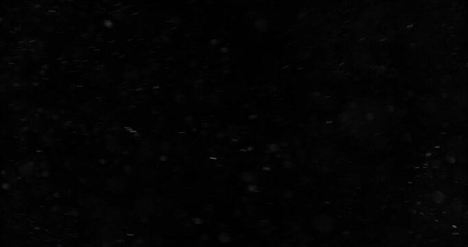 Super slow motion falling snow or dust particles isolated on a black background. Abstract atmospheric SFX overlay with floating debris, cinematic texture and dark visual effect.