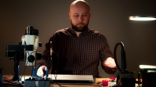 Repair Technician Working on Laptop at Electronics Bench