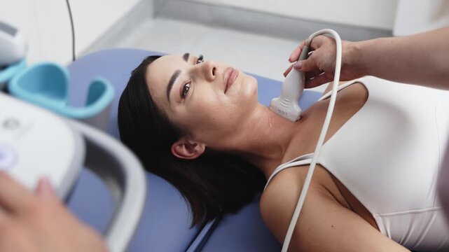 Medical professional performing a thyroid ultrasound examination on a young woman in close-up. Concept thyroid health, endocrinology, ultrasound diagnostics, preventive medicine, medical examination.