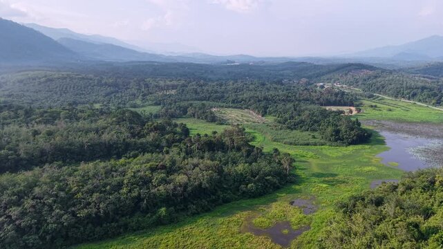 Aerial view of mountain valley with lush green forests. Winding river cuts through the landscape at Tasik Raban