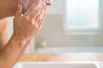 Fototapeta premium A man washing his face with soap and water in a clean bathroom