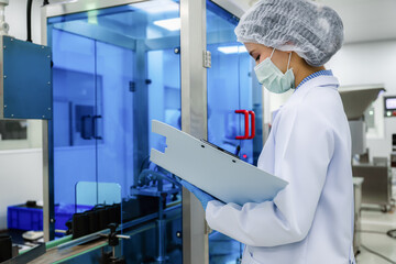 Fototapeta na wymiar Close up of Asian female scientist checking black plastic bottle packaging machine inside laboratory. concept of pharmaceutical medicine production line quality control.
