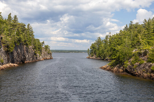 A close up view of the waterway "Hole in the Wall" near Parry Sound from the 30,000 Islands cruise, highlighting rugged cliffs and lush greenery beneath expansive skies.