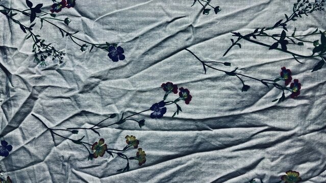 crumpled grey linen fabric showcasing dark blue and maroon botanical sprigs on textured organic cloth background