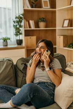 Woman relaxing at home talking on phone eating popcorn