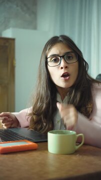 Young Hispanic businesswoman in a modern office looking at the camera and making a silence gesture with her finger over her lips, asking for quiet in a professional workplace.
