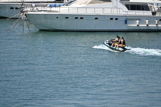 Yacht in a Marina with People Riding a Jet Ski Nearby