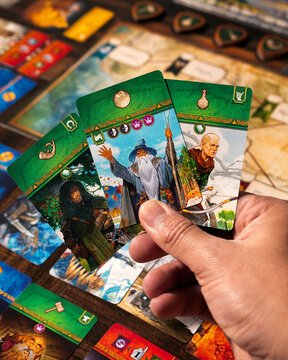 Detailed macro portrait photography of player hand holding Lord of the Rings hero cards featuring Gandalf Legolas and Aragorn character representations