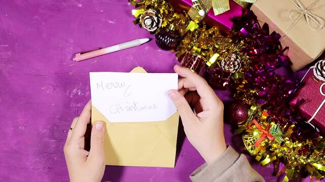 white card reading 'Merry Christmas' against a colorful backdrop of wrapped presents, tinsel, and festive bokeh lights, conveying warmth and holiday cheer