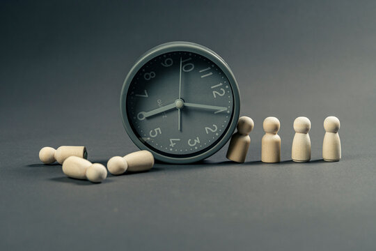 Wooden figurine supporting the weight of time while others wait in line